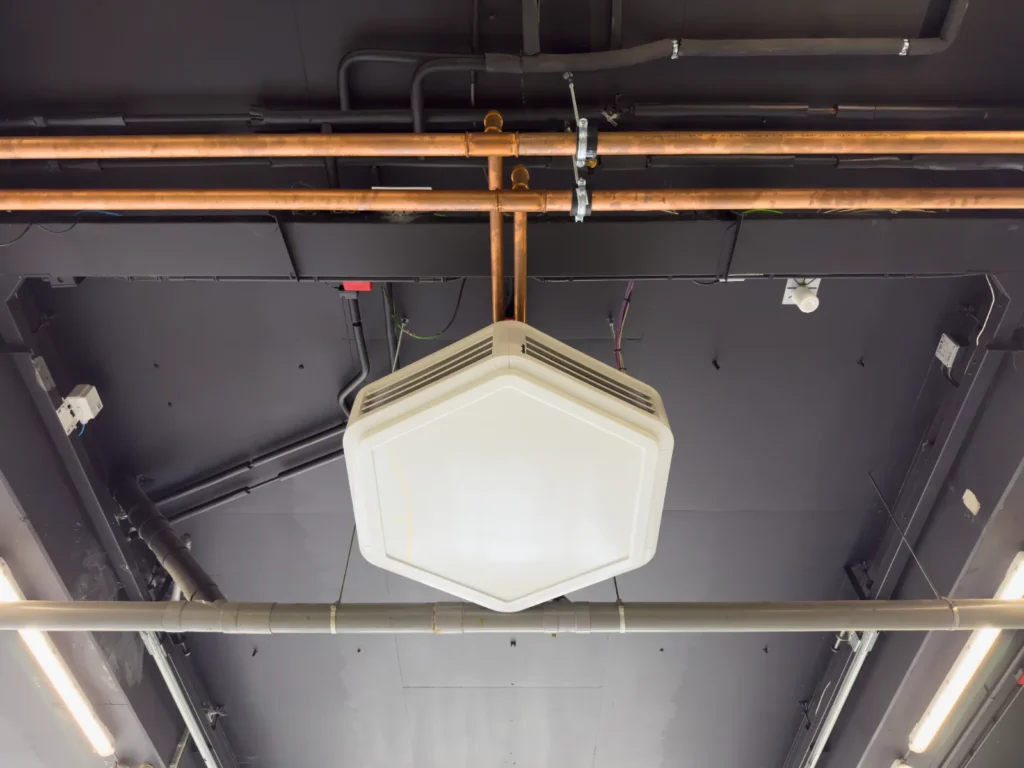 Detail van de fancoil-unit, met de koperen aansluiting van onderaf gezien.